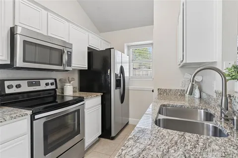 a kitchen with granite countertop a stove microwave and refrigerator