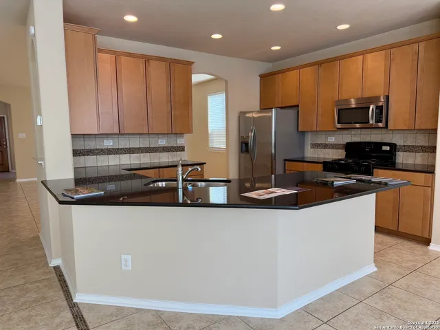 a kitchen with stainless steel appliances granite countertop a sink a stove and a refrigerator