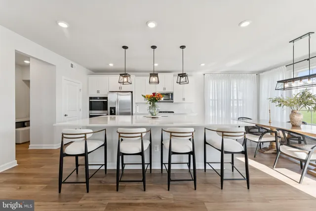 a kitchen with stainless steel appliances kitchen island granite countertop a table chairs and a wooden floor