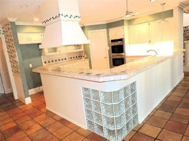 a view of kitchen with stainless steel appliances kitchen island granite countertop a sink and cabinets
