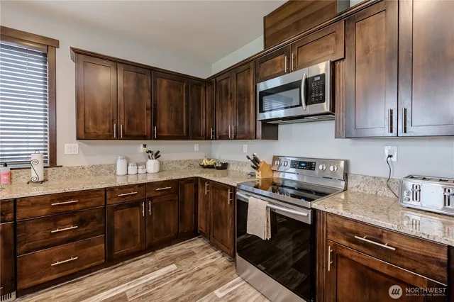 a kitchen with stainless steel appliances granite countertop wooden cabinets a stove top oven a sink and dishwasher