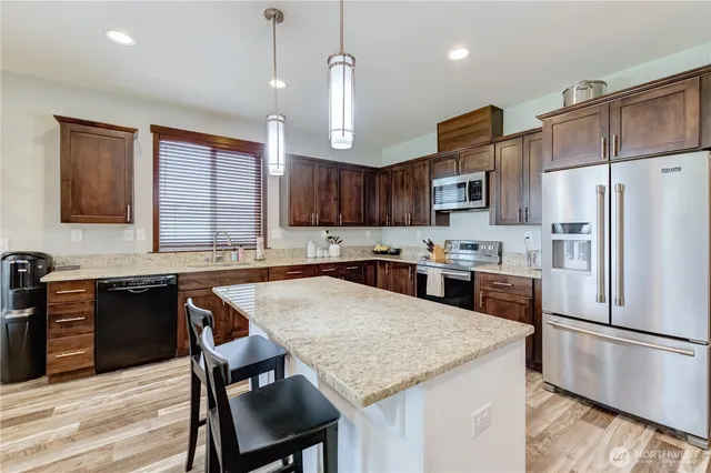 a kitchen with stainless steel appliances granite countertop a stove refrigerator a sink a stove and a wooden floors
