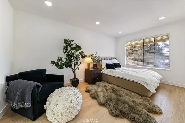 a bedroom with a bed table flowerpot and window