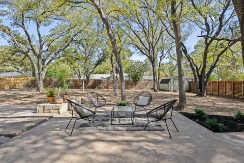 a view of a patio with table and chairs and a large tree