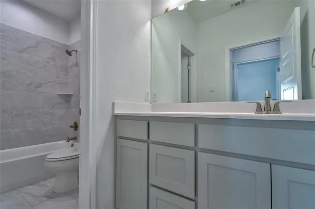 a bathroom with a bathtub sink vanity mirror and toilet