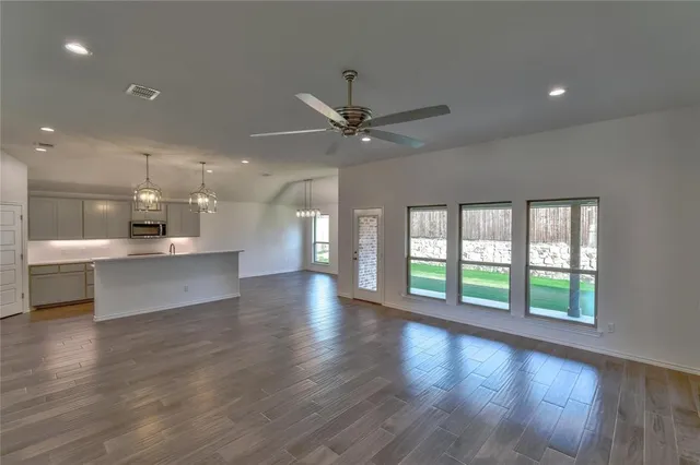 a view of an empty room with a kitchen and wooden floor