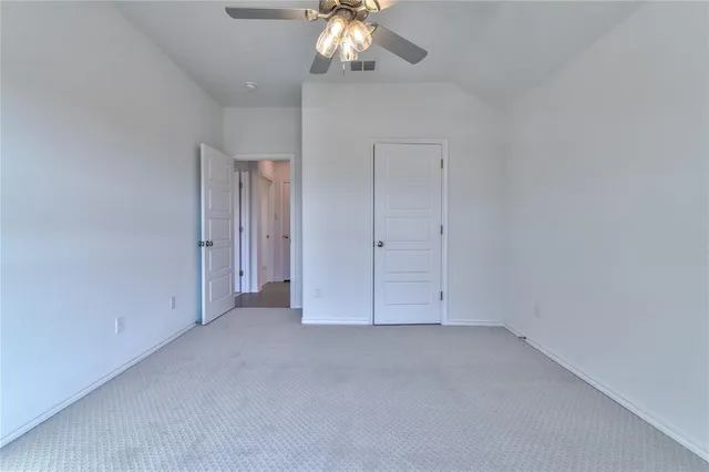 an empty room with a chandelier fan and wooden floor
