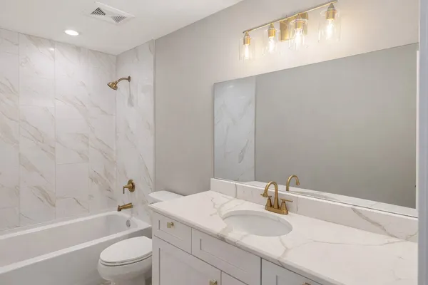 a bathroom with a granite countertop sink a toilet and bathtub