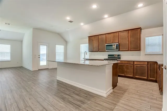 a kitchen with stainless steel appliances granite countertop a stove a sink and a microwave