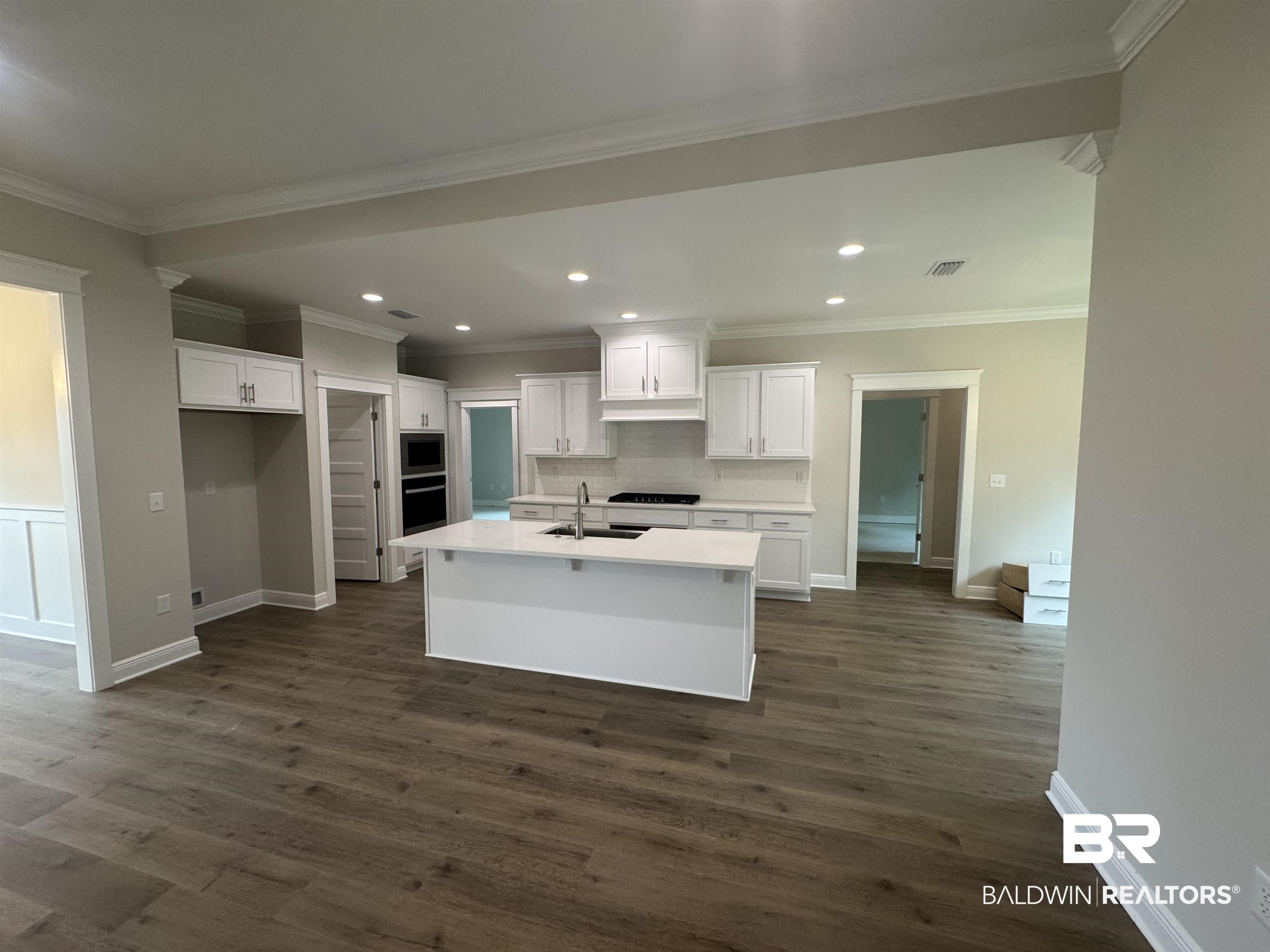 8090 Calverton Street, Unit 23 Foley, AL 36535 - Photo 4 of 30 Kitchen featuring crown molding, white cabinetry, dark hardwood / wood-style floors, sink, and a kitchen island with sink