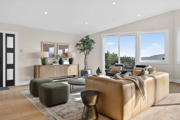 a living room with furniture a large window and wooden floor