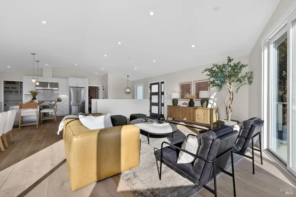 a kitchen with stainless steel appliances granite countertop a stove a refrigerator a kitchen island a dining table and chairs with wooden floor