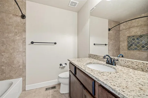 a bathroom with a granite countertop sink a toilet and shower