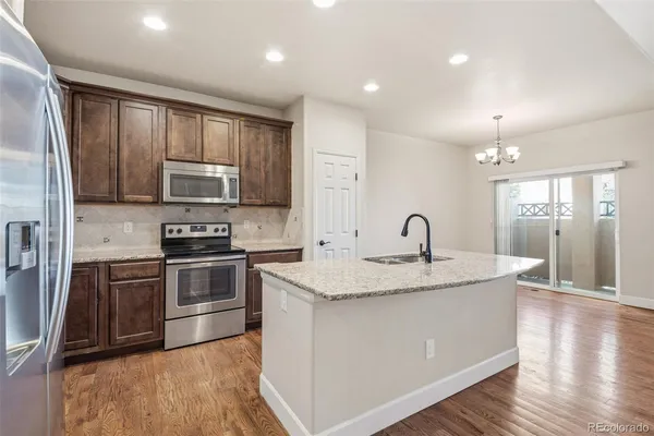 a kitchen with stainless steel appliances granite countertop a stove top oven a sink and a refrigerator