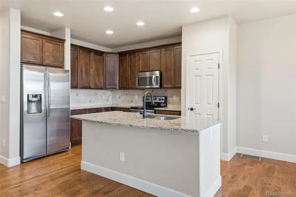 a kitchen with stainless steel appliances granite countertop a refrigerator a sink a stove and oven