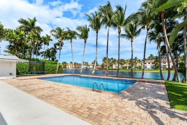 a view of swimming pool with outdoor seating and trees in the background