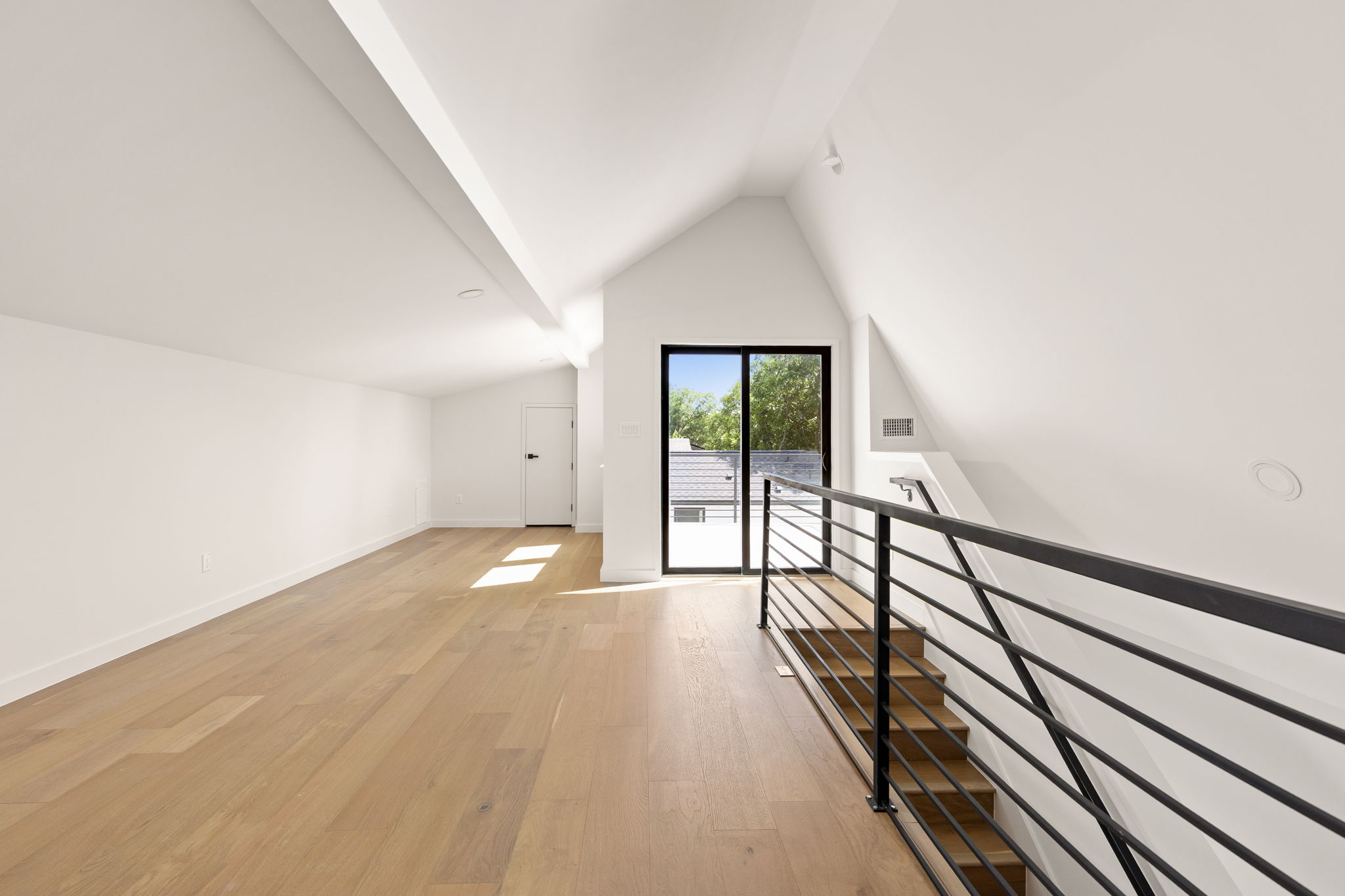 2717 Lyons Road, Unit 1 Austin, TX 78702 - Photo 28 of 40 A spacious upper-level area offers hardwood floors, abundant natural light, and modern railing overlooking the staircase.