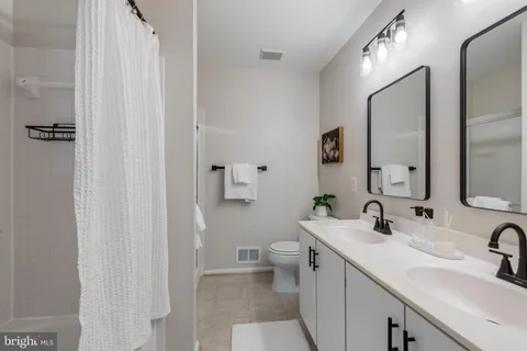 a bathroom with a double vanity sink toilet and mirror