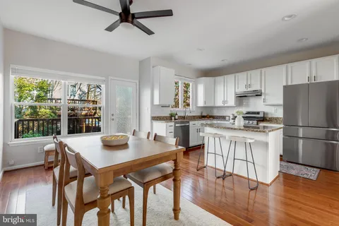 a kitchen with stainless steel appliances granite countertop a stove a refrigerator a dining table and chairs with wooden floor