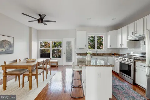 a kitchen with stainless steel appliances a stove a sink dishwasher a dining table and chairs with wooden floor