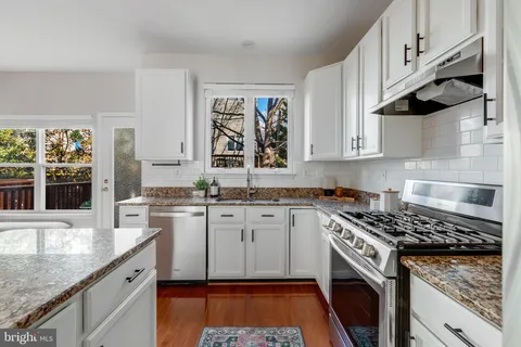 a kitchen with granite countertop a sink a stove and cabinets