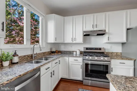 a kitchen with granite countertop a sink stainless steel appliances and cabinets