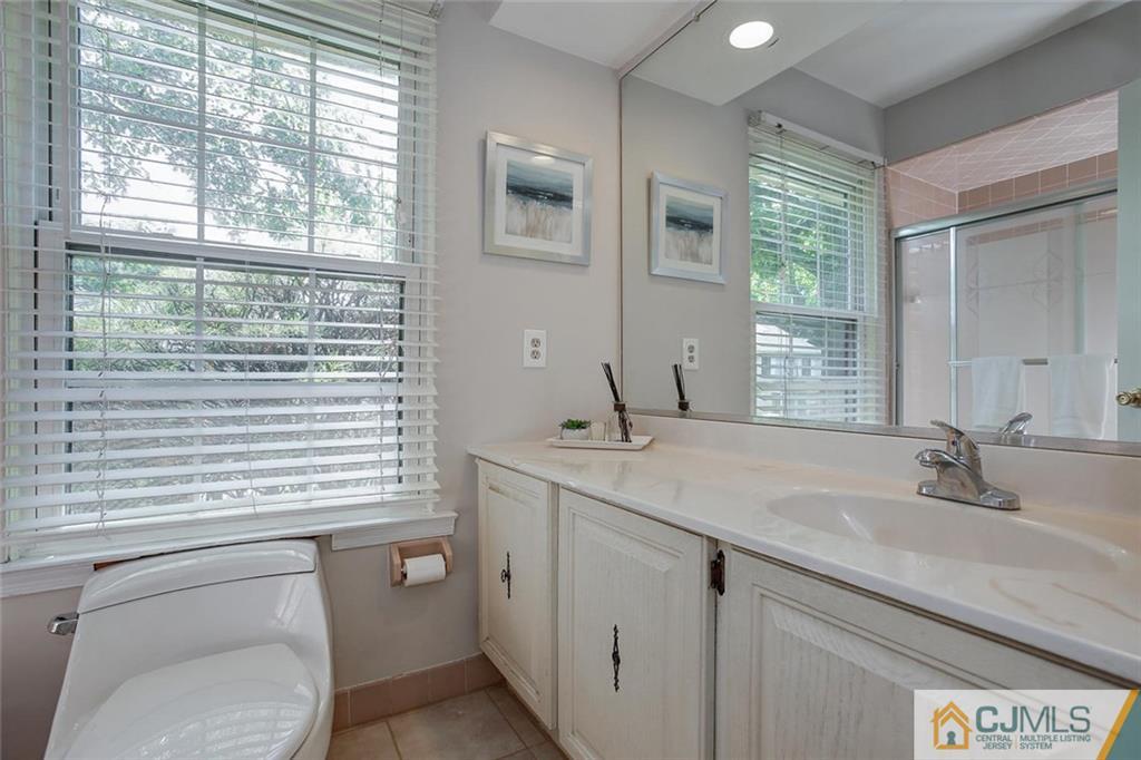1901 Timber Oaks Road Edison, NJ 08820 - Photo 21 of 23 a bathroom with a toilet a sink a mirror and next to a window