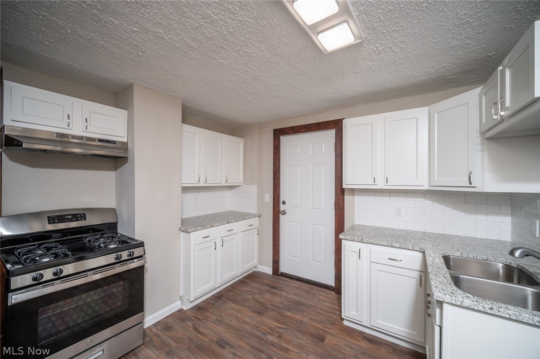 809 Wales Road Northeast Massillon, OH 44646 - Photo 6 of 15 Kitchen featuring white cabinets, dark hardwood / wood-style flooring, backsplash, stainless steel range with gas stovetop, and sink