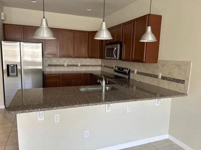 a kitchen with stainless steel appliances granite countertop a sink a stove and a refrigerator