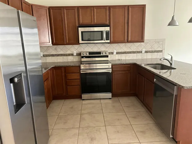 a kitchen with granite countertop a refrigerator and a stove top oven