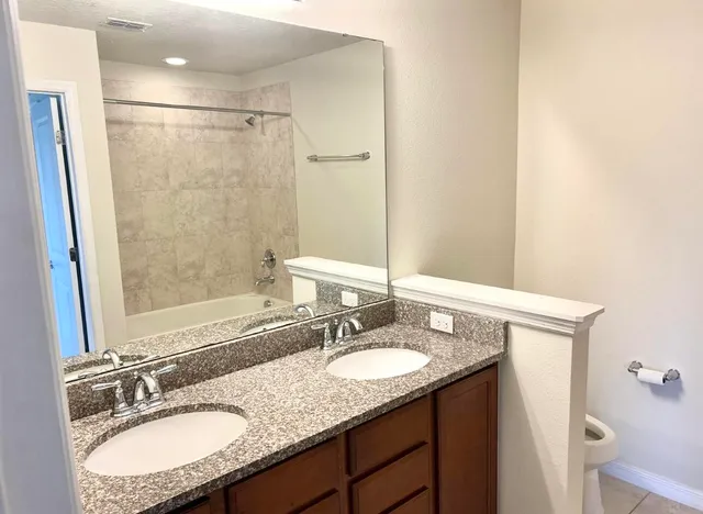 a bathroom with a granite countertop sink a mirror a shower and a vanity