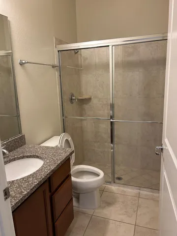 a bathroom with a granite countertop sink toilet and shower