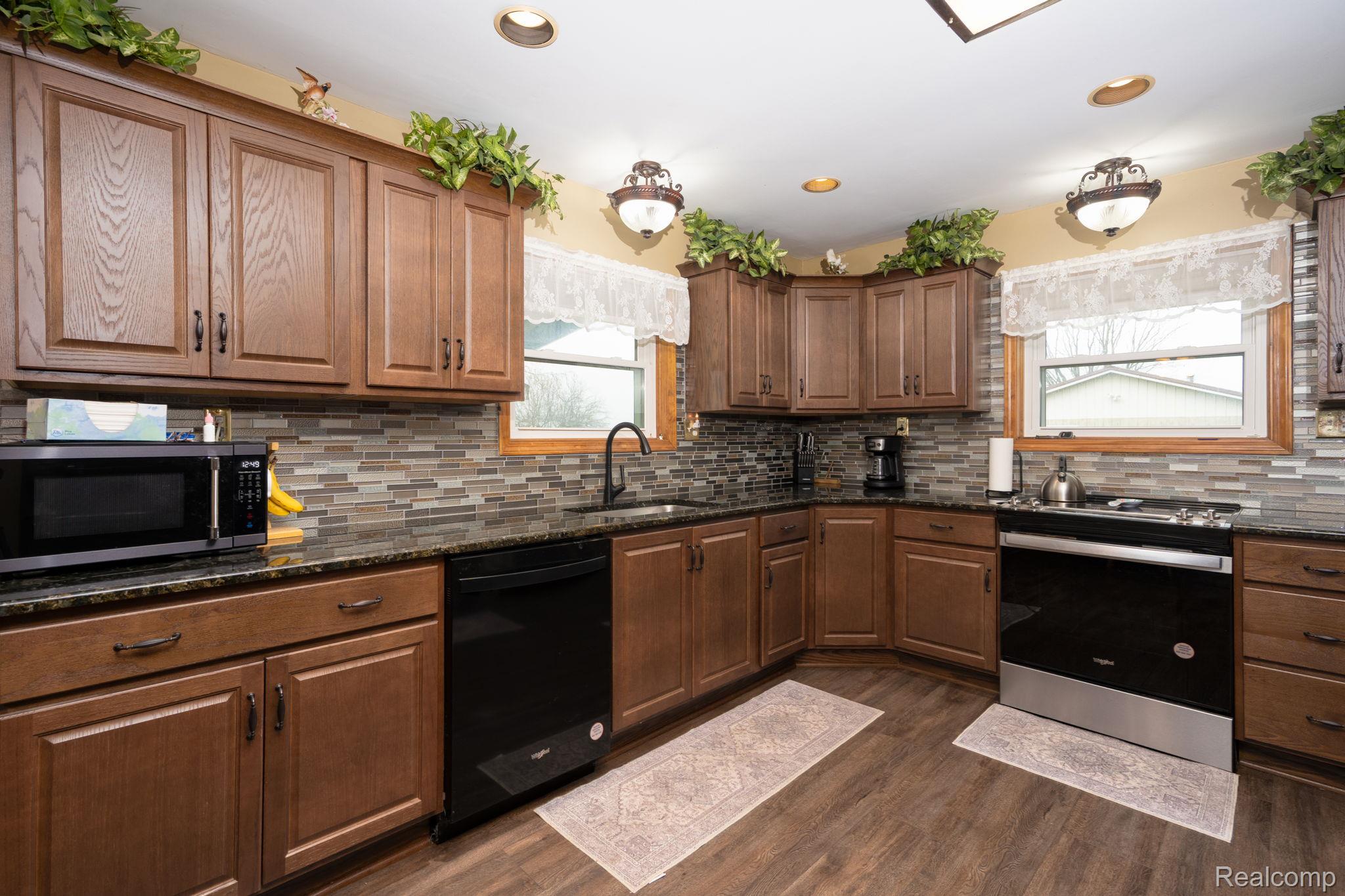2890 Graham Road Imlay City, MI 48444 - Photo 13 of 33 Kitchen featuring stainless steel appliances, dark stone counters, dark wood-style floors, wood finish cabinets, and recessed lighting