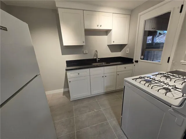 a kitchen with granite countertop a sink stove and cabinets