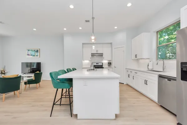 a kitchen with kitchen island a sink a counter top space and living room view