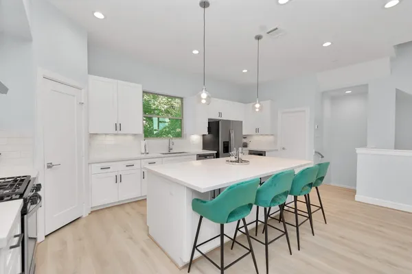 a kitchen with stainless steel appliances a dining table chairs stove sink and cabinets