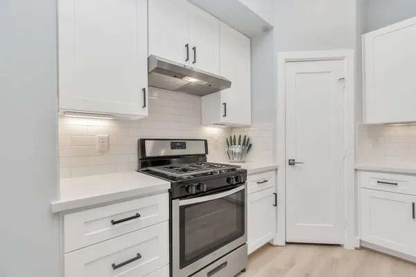 a kitchen with white cabinets and appliances