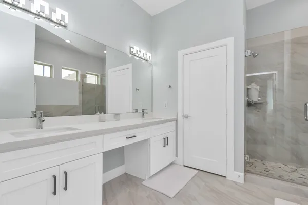 a bathroom with a double vanity sink mirror and shower