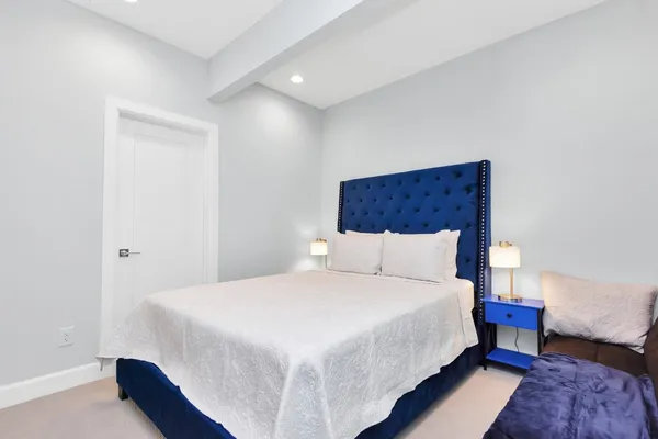 a large bed sitting in a bedroom next to a lamp with a rug