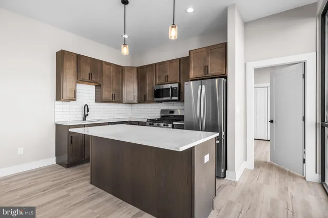 a kitchen with stainless steel appliances a sink stove refrigerator and cabinets