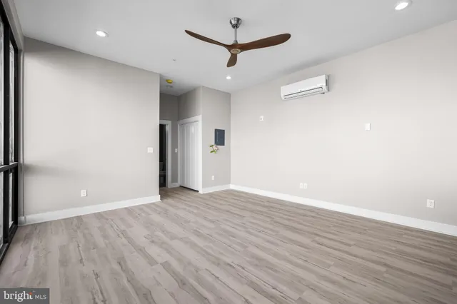 an empty room with wooden floor and a ceiling fan