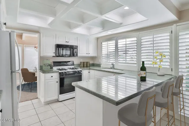 a kitchen with a stove a sink a microwave a dining table and chairs