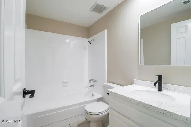 a bathroom with a granite countertop sink a toilet and a mirror