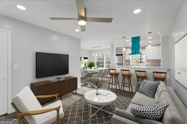 a living room with furniture a flat screen tv and kitchen view