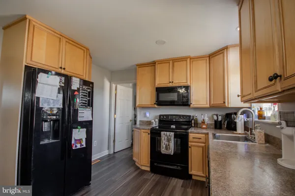 a kitchen with stainless steel appliances granite countertop a refrigerator a stove top oven a sink and dishwasher with wooden floor