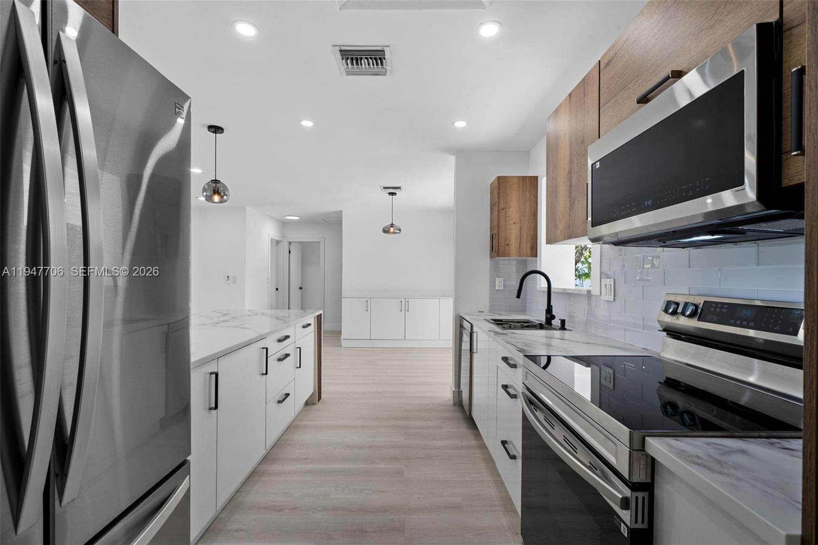 709 Southwest 4th Court Hallandale Beach, FL 33009 - Photo 12 of 59 a kitchen with stainless steel appliances a stove microwave and a refrigerator