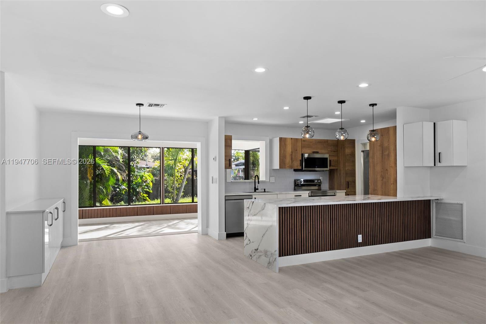 709 Southwest 4th Court Hallandale Beach, FL 33009 - Photo 5 of 59 a open kitchen with stainless steel appliances granite countertop a stove top oven a sink dishwasher a refrigerator and a dining table with wooden floor
