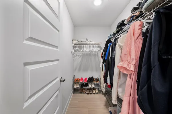 a view of walk in closet with clothes and shoes
