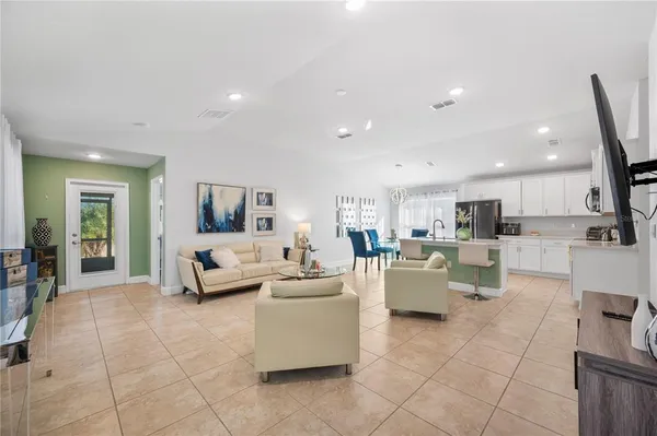 a living room with couches and kitchen view with wooden floor