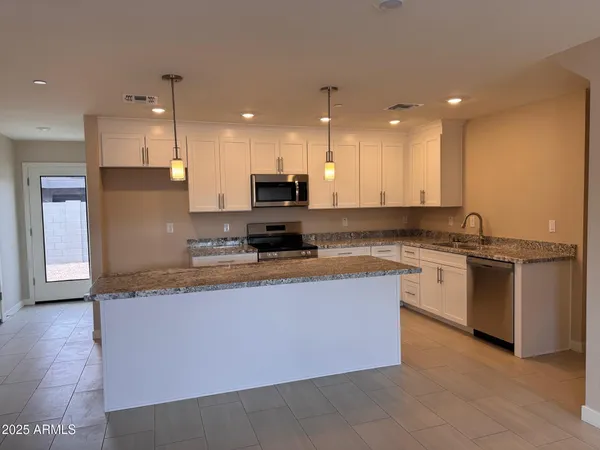 a large kitchen with granite countertop a large counter top stainless steel appliances and cabinets